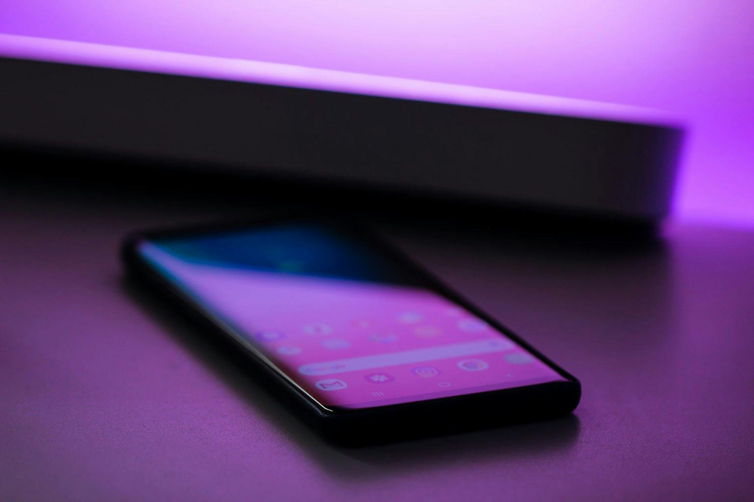 Phone laying on table, with purple lighting