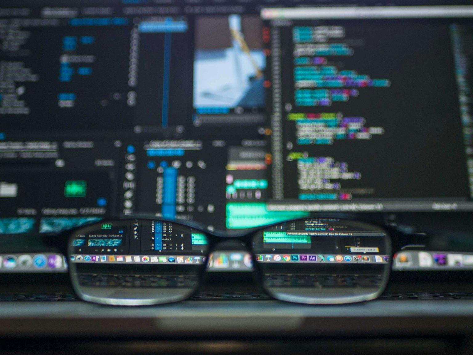 Glasses on desk in front of screen with code