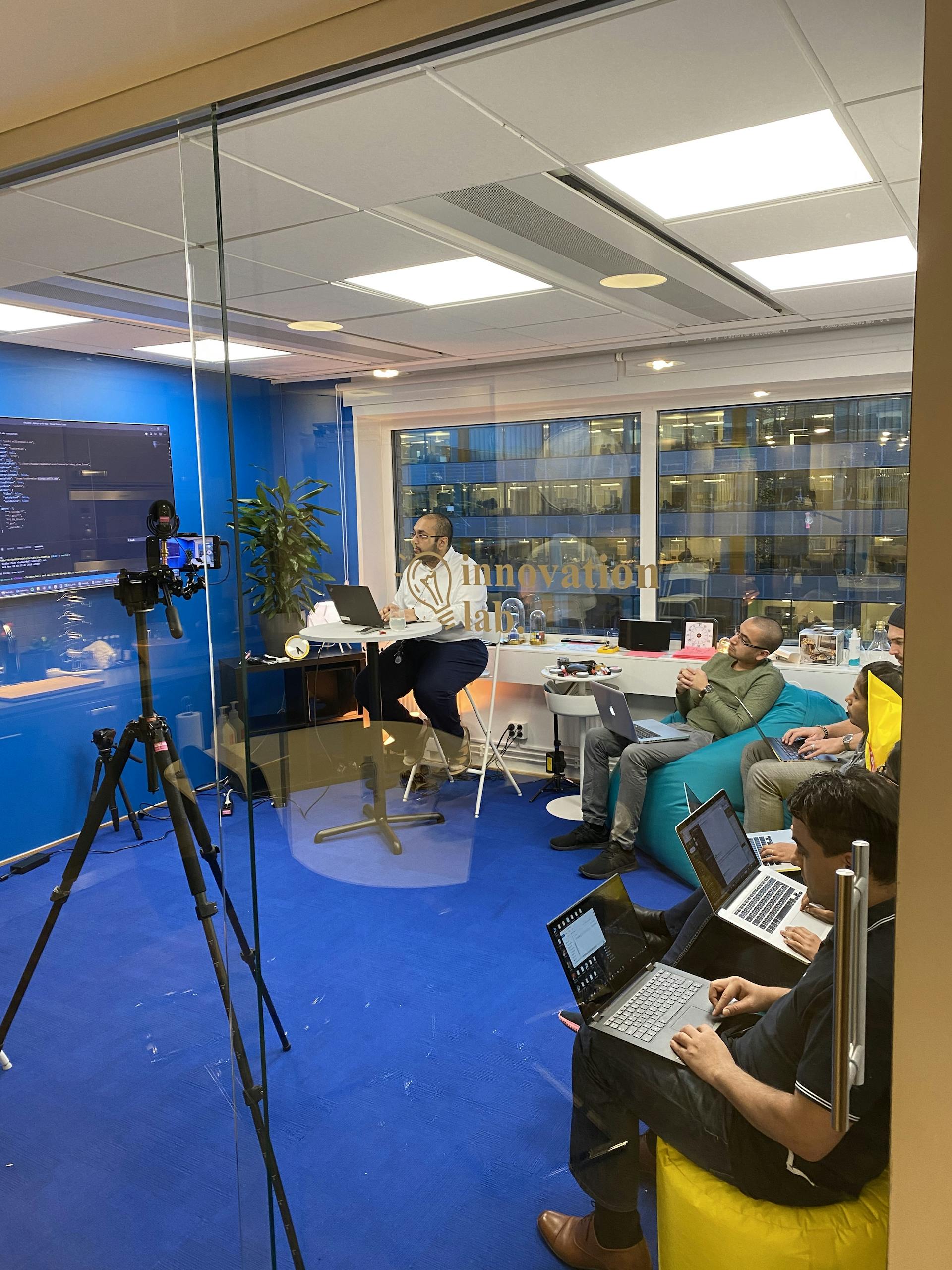People sitting in a blue office room with bean bags, watching a presentation